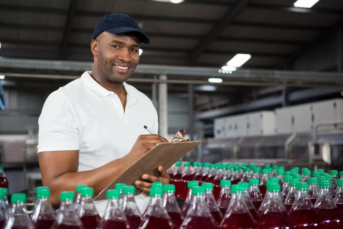 Junger männlicher Arbeiter macht Notizen in einer Saftfabrik.