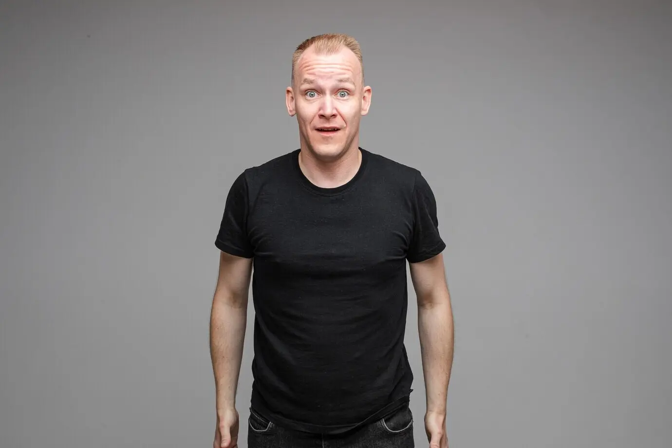 Halbfiguriges Foto eines emotionalen Mannes in Schwarz, der den Mund öffnet.